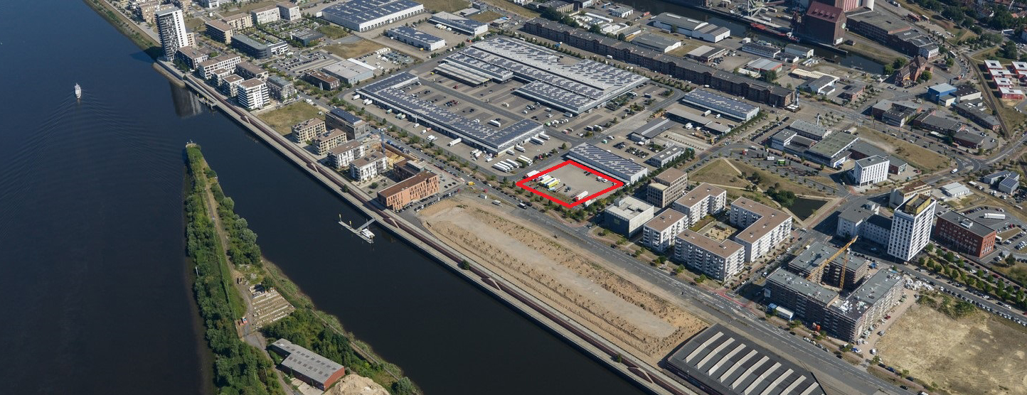 Luftbild von der Überseestadt Bremen, auf dem eine quadratische Fläche, die zum Verkauf ausgeschrieben wird, rot markiert ist. - Quelle: WFB / Christian Ring