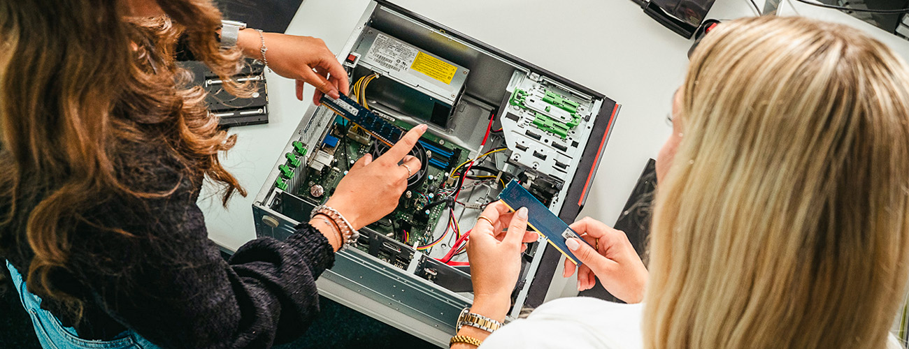 Zwei junge Frauen stehen vor einem geöffneten Gehäuse eines PCs. Beide halten Arbeitsspeicherplatten in der Hand. - Quelle: WFB/Jann Raveling