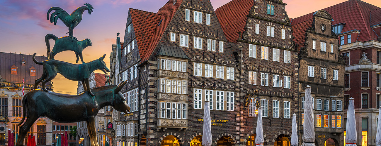 Bremer Wahrzeichen: Die Stadtmusikanten-Bronze im Abendlicht. Dahinter die historischen Gebäude rund um den Bremer Marktplatz.