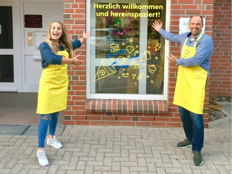 A salesman and a saleswoman stand in front of a grocery shop A salesman and a saleswoman stand in front of a grocery shop