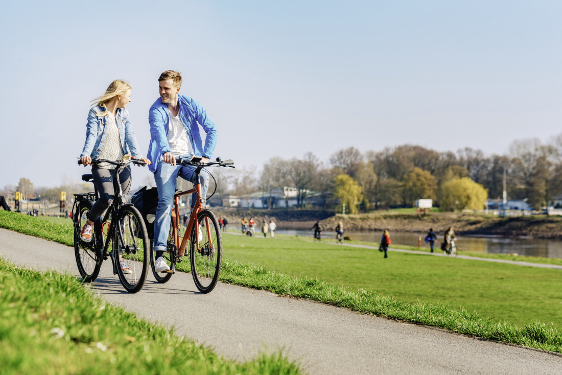 Zwei Menschen fahren Fahrrad am Deich