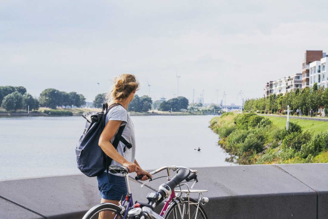 Frau mit Fahrrad steht am Wasser