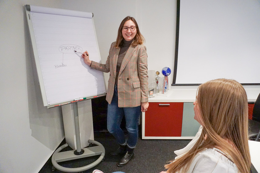 Eine Frau schreibt etwas auf ein Whiteboard. Eine andere sieht ihr zu