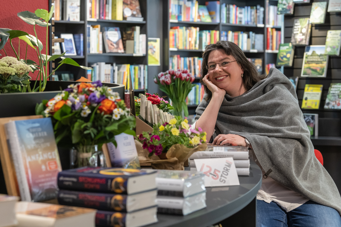 Eine Frau sitzt in einer Buchhandlung an einem Tresen Eine Frau sitzt in einer Buchhandlung an einem Tresen