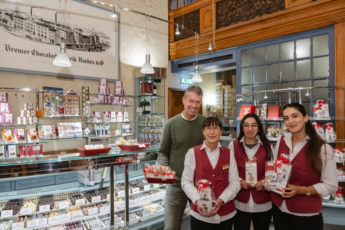 Ein Mann und drei Frauen stehen vor einer Pralinentheke