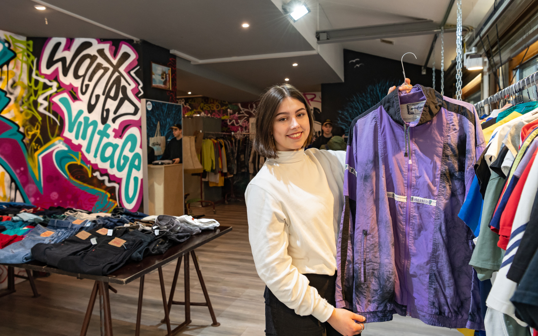 Eine Frau steht in einem Laden und hält eine Jacke hoch Eine Frau steht in einem Laden und hält eine Jacke hoch