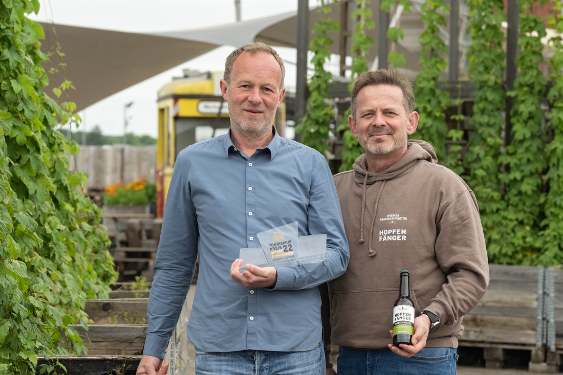 Zwei Männer mit dem Tourismuspreis und Flasche Bier