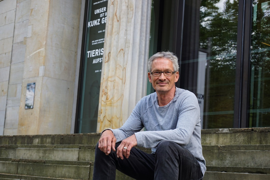 Jens-Joost Krüger sitzt auf den Treppen der Kunsthalle in Bremen.