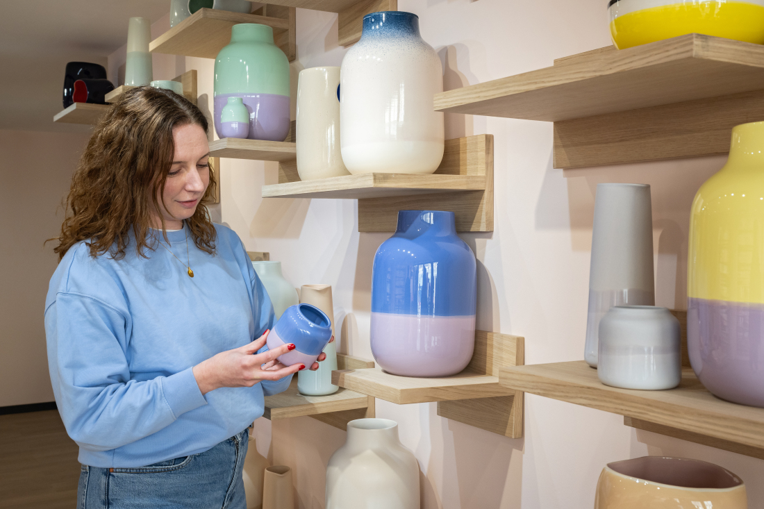 Eine Frau hält eine Vase in einem Geschäft hoch Eine Frau hält eine Vase in einem Geschäft hoch