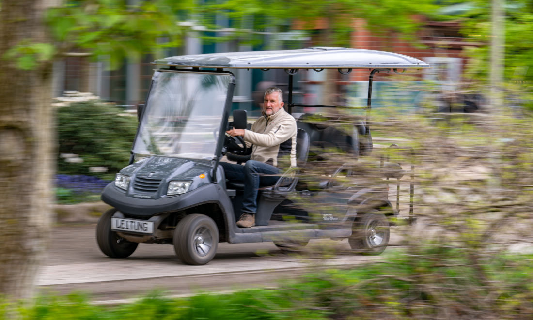 Parkleiter Hartwig Schepker sitzt in einem Elektromobil (Golfkart) und fährt durch den Park.