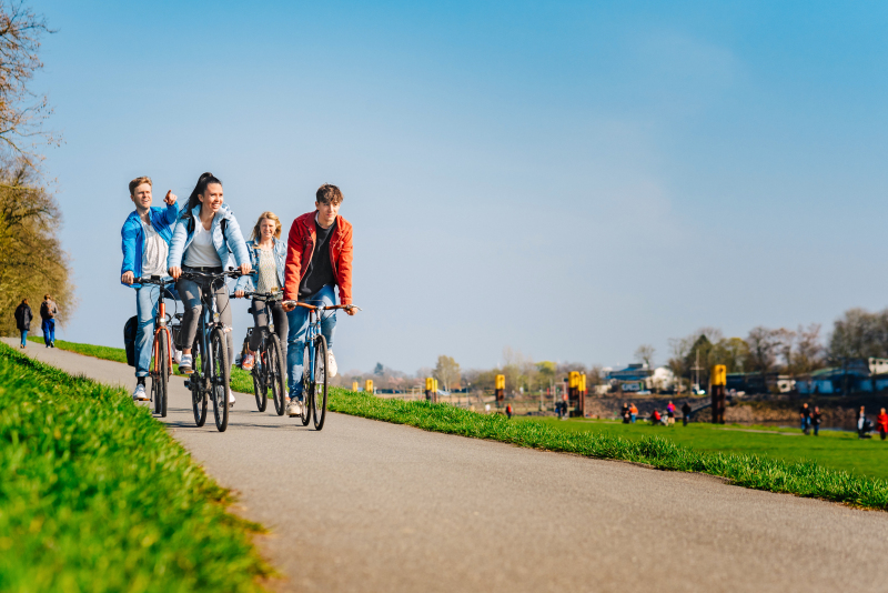 Vier Menschen sitzen auf ihren Fahrrädern und fahren am Osterdeich.