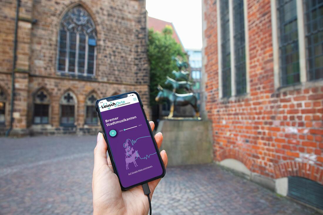 Eine Hand hält ein Handy vor den Bremer Stadtmusikanten Eine Hand hält ein Handy vor den Bremer Stadtmusikanten