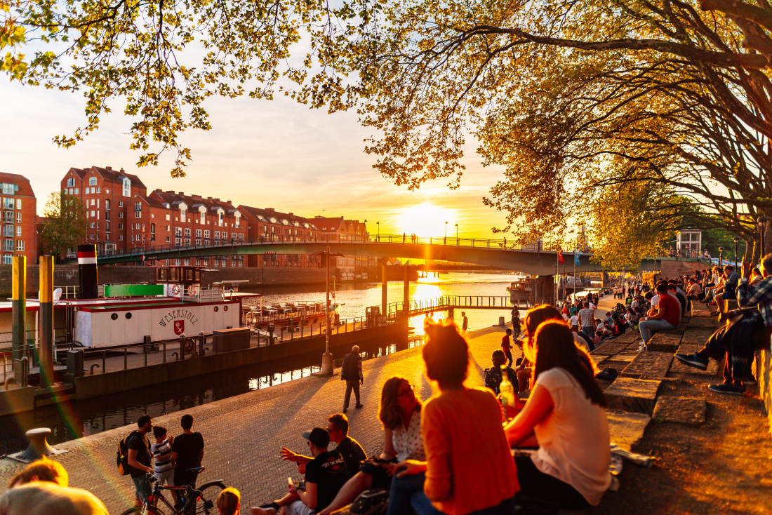 Schlachte in Bremen: Menschen sitzen in der Abendstimmung an der Weser