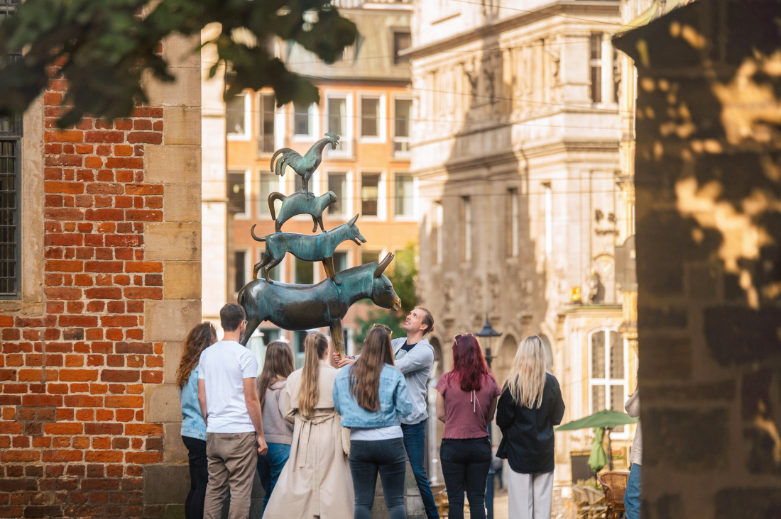 Mehrere Personen stehen vor den Stadtmusikanten und fassen die Vorderbeine des Esels an.