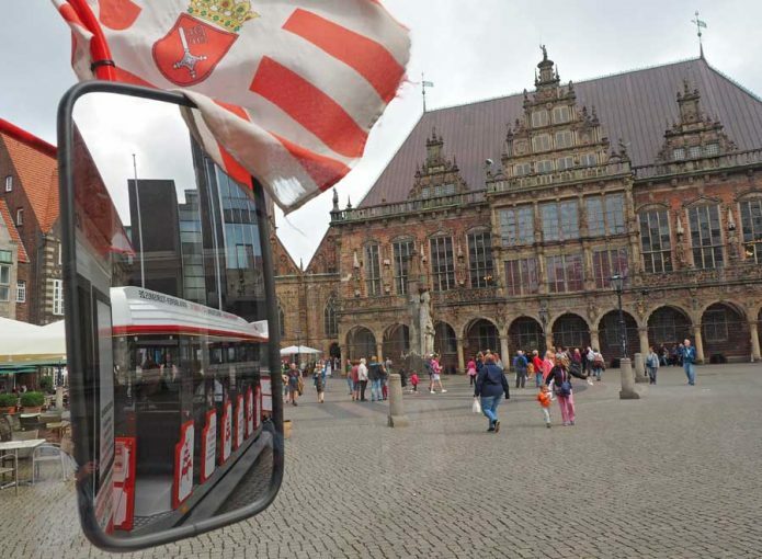 Bremer Marktplatz und Außenspiegel des Stadtmusikanten-Express mit Bremer Flagge